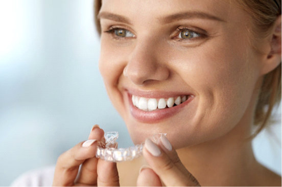 Woman placing a clear Invisalign aligner on her teeth